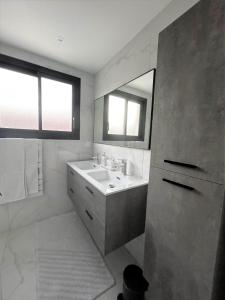 Baño blanco con lavabo y espejo en LA MAISON DE MARIE A 8 mn des plages, en Perpiñán