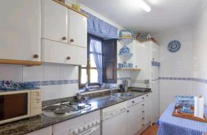 kuchnia z białymi szafkami oraz urządzeniami niebiesko-białymi w obiekcie Casa LaCarusa 28 