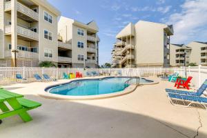 a swimming pool with chairs and tables and condos at Bayfront Pensacola Beach Condo with Pool and Elevator in Pensacola Beach