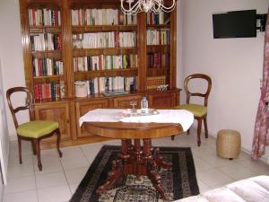 a dining room with a table and chairs and a book shelf at Les Petunias in Hugier