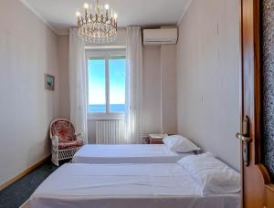 1 dormitorio con 2 camas, lámpara de araña y ventana en Grande Appartamento Vista Mare, en Varazze