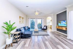 a living room with a blue couch and a tv at Cozy 2BR Condo - Private Balcony - Near Disney in Orlando