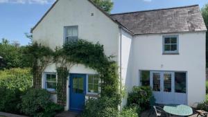 ein weißes Haus mit blauer Tür in der Unterkunft Orchard Cottage, Landimore in Cheriton