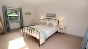 ein Schlafzimmer mit einem Bett, zwei Tischen und einem Fenster in der Unterkunft Orchard Cottage, Landimore in Cheriton