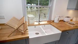 eine Küchentheke mit Spüle und Fenster in der Unterkunft Orchard Cottage, Landimore in Cheriton + 16 Fotos