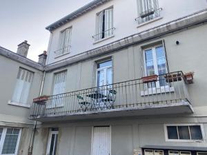 ein weißes Gebäude mit einem Balkon mit Stühlen darauf in der Unterkunft Appartement luxueux rénové avec balcon & garage in Troyes