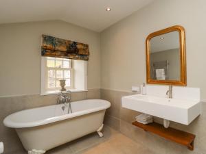 a bathroom with a tub and a sink and a mirror at Hilltop House in Starbotton