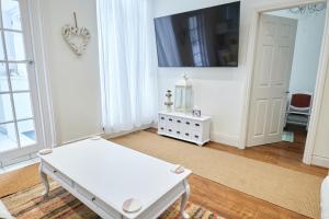 a white living room with a table and a tv at Super Stylish Flat Very Close to Freeman Hospital! in High Heaton