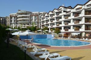 a large apartment building with a swimming pool and chairs at Bratanov Royal Palm Apartments in Sveti Vlas