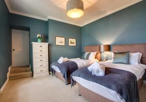 two beds in a bedroom with blue walls at Orchard Cottage in Newlyn