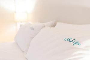 Una cama blanca con almohadas blancas con palabras sin mentiras en MeYia studios en Tesalónica