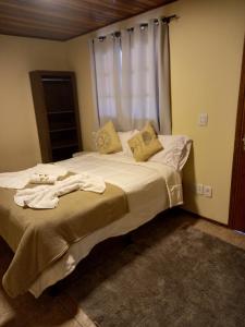 1 dormitorio con 1 cama con toallas en Pousada serrano, en Monte Verde