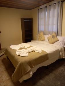 1 dormitorio con 1 cama con toallas en Pousada serrano en Monte Verde