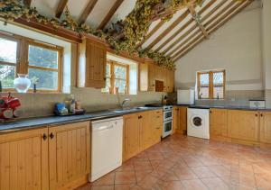 a kitchen with wooden cabinets and a white dishwasher at Rectory Barn in Ashwellthorpe