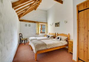 a bedroom with two beds and a chair at Rectory Barn in Ashwellthorpe