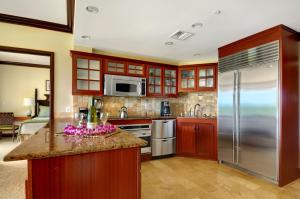 a kitchen with wooden cabinets and stainless steel appliances at Waipouli Beach Resort Penthouse Exquisite Ocean & Pool View Condo! in Kapaa