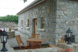 einen Tisch und Stühle außerhalb eines Steingebäudes in der Unterkunft Traditional Stone Cottage 300 years+ in Galway