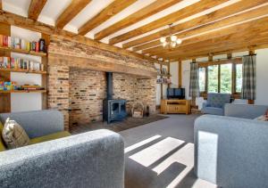 a living room with a fireplace and a brick wall at Stone Cottage in Darsham