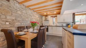 una cucina con tavolo in legno e parete in pietra di The Granary, Llanmadoc a Llanmadoc