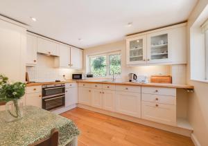 a kitchen with white cabinets and a table at Combe Way Cottage in Branscombe