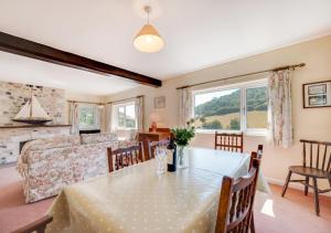a dining room with a table and a bedroom at Combe Way Cottage in Branscombe
