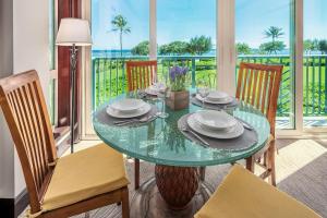 a dining room with a glass table and chairs at Waipouli Beach Resort Spectacular Luxury Oceanfront Condo Sleeps 8 AC Pool in Kapaa