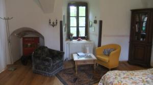 a bedroom with a bed and two chairs and a fireplace at Schloss Höllrich in Karsbach