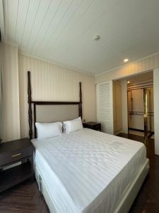 a bedroom with a large bed with white sheets at Grand Florida BeachFront Resort NaJomtien Pattaya in Na Jomtien
