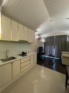 a kitchen with white cabinets and a living room at Grand Florida BeachFront Resort NaJomtien Pattaya in Na Jomtien