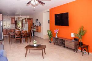 a living room with an orange wall with a tv at Cozy Downtown Boquete Chalet in Bajo Boquete