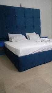a bed with a blue headboard with two pillows on it at Johar Hill view Guest House in Karachi