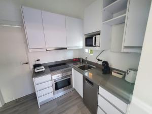 a small kitchen with white cabinets and a sink at Chalet Luxury with privacy and Jacuzzi in Maspalomas