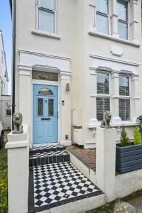 une porte bleue sur une maison blanche avec un sol en damier dans l'établissement Wembley Luxury Residence- Opulence House, à Londres