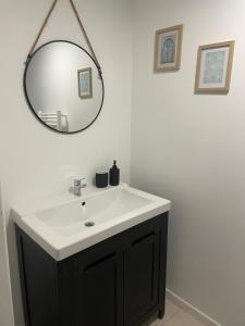 a bathroom with a black and white sink and a mirror at La chambre verte in Bédée