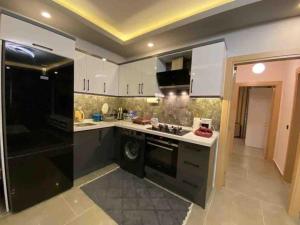 a kitchen with white cabinets and a black appliance at Center apartment in Fethiye