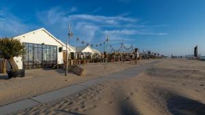 uma praia com um edifício e bandeiras na areia em Strandhuis aan zee em Noordwijk