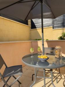 einen Tisch und Stühle unter einem Sonnenschirm auf einer Terrasse in der Unterkunft La chambre verte in Bédée