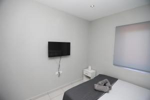 a white room with a bed and a flat screen tv at iLposto Up in Kavala