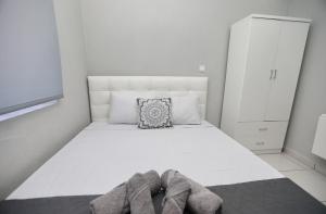 a bedroom with a white bed with shoes on it at iLposto Up in Kavala