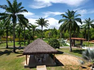 a hut with chairs and palm trees in a park at Pousada Pratigi in Ituberá