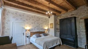 1 dormitorio con cama y pared de piedra en Manoir La Cerise, en Fougerolles