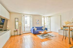 ein Wohnzimmer mit einem blauen Sofa und einem Tisch in der Unterkunft Bright Parisian Flat - Marais in Paris