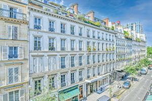 ein großes weißes Gebäude mit Fenstern auf einer Straße in der Unterkunft Bright Parisian Flat - Marais in Paris