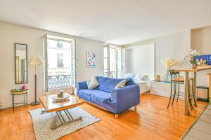 ein Wohnzimmer mit einem blauen Sofa und einem Bett in der Unterkunft Bright Parisian Flat - Marais in Paris