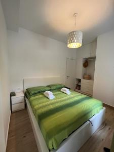 a bedroom with a large bed with a green blanket at V&T Apartment in Brela