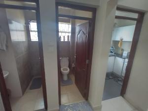 a bathroom with a toilet and a wooden door at Kathy's Two Bedrooms in Nairobi