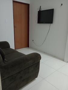 a living room with a couch and a television on a wall at Apartamento Mobiliado no Centro da Cidade in Imperatriz