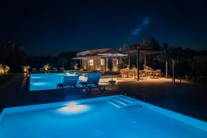 a swimming pool at night with chairs and a table at Nestor Luxury Villas with Private Pools in Romanós