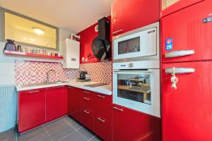 - une cuisine rouge avec des placards rouges et un four micro-ondes dans l'établissement kerbonne furnished flat, à Brest