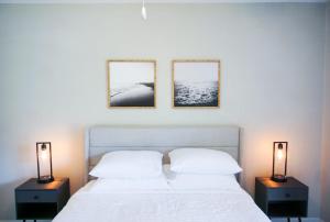 坦帕的住宿－Serene Townhouse near Moffitt, Advent, & USF，一间卧室配有一张带两盏灯的床,墙上有两张照片